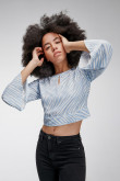 Blusa en tela fluida, con cuello redondo y abertura en ojal en frente. Fajón inferior para anudar en espalda.