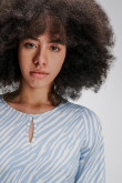 Blusa en tela fluida, con cuello redondo y abertura en ojal en frente. Fajón inferior para anudar en espalda.
