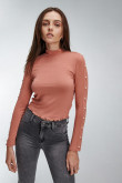 Camiseta unicolor manga larga, con cuello alto y perlas sobre manga.