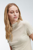 Camiseta femenina unicolor con perlas sobre frente y mangas.