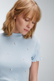 Camiseta femenina unicolor con perlas sobre frente y mangas.