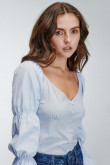Blusa unicolor de silueta ajustada en tela liviana con recogido en cabeza de manga y encauchado en manga.