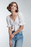 Blusa unicolor en tela lisa con escote y mangas con encauchado en puño.