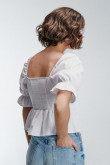 Blusa unicolor en tela lisa con escote y mangas con encauchado en puño.